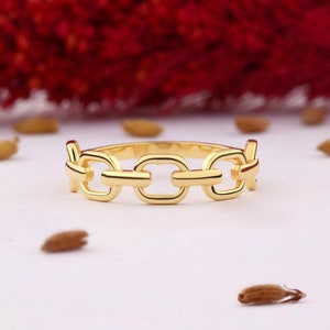 May include: Gold chain link ring with a simple design. The ring is made of a thick, chunky chain link and is a statement piece.