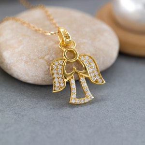 K&ouml;nnte beinhalten: Eine goldene Engels-Anh&auml;nger-Kette mit klaren Zirkonia-Steinen. Der Engel befindet sich in einer betenden Position mit ausgebreiteten Fl&uuml;geln.