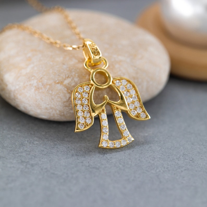 K&ouml;nnte beinhalten: Eine goldene Engels-Anh&auml;nger-Kette mit klaren Zirkonia-Steinen. Der Engel befindet sich in einer betenden Position mit ausgebreiteten Fl&uuml;geln.
