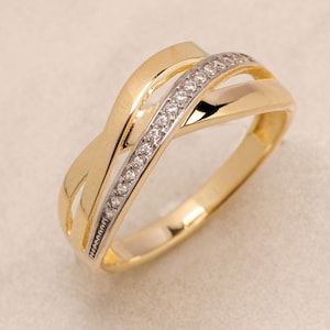 Könnte beinhalten: Ein goldener Ring mit einem Diamantenband. Der Ring hat ein verdrehtes Design mit drei Bändern.