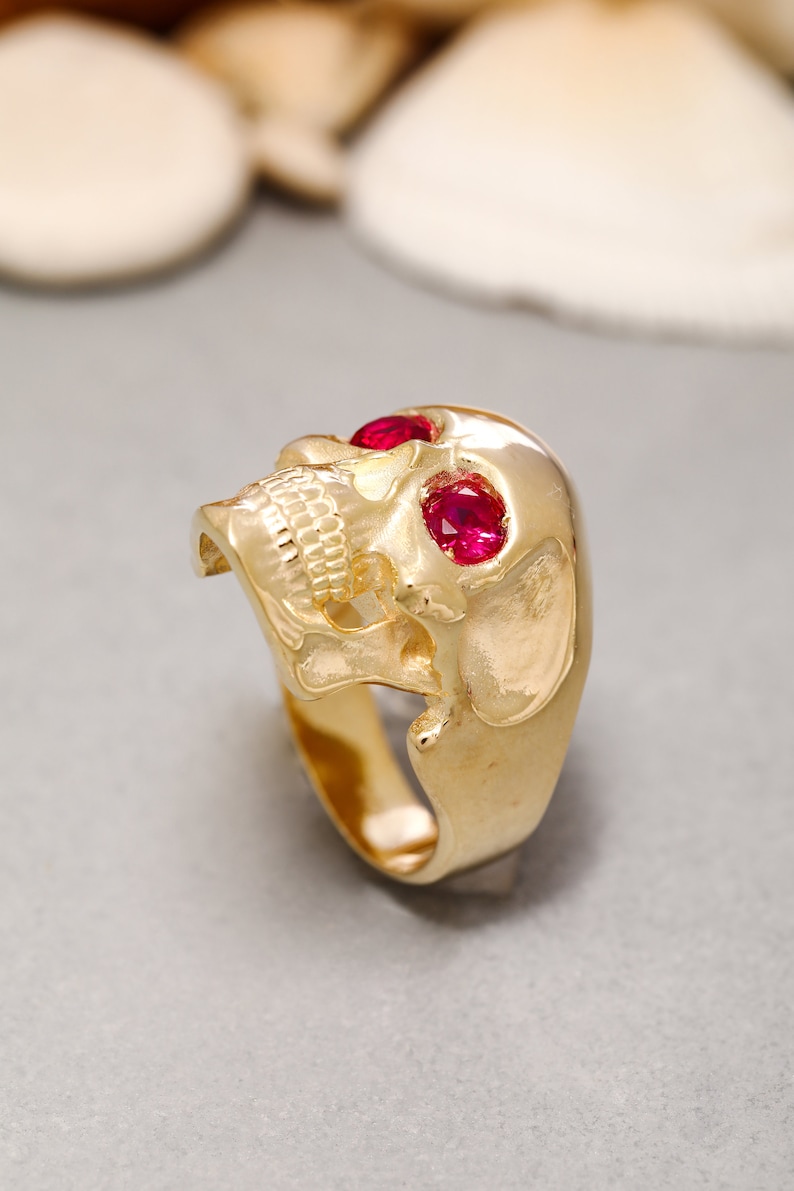 May include: A gold skull ring with two red gemstone eyes.