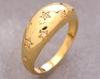 May include: A polished gold dome ring featuring a series of engraved star motifs across the surface. Each star is centered with a small, clear, sparkling gemstone, creating a celestial pattern on the smooth, rounded band of the jewelry piece.