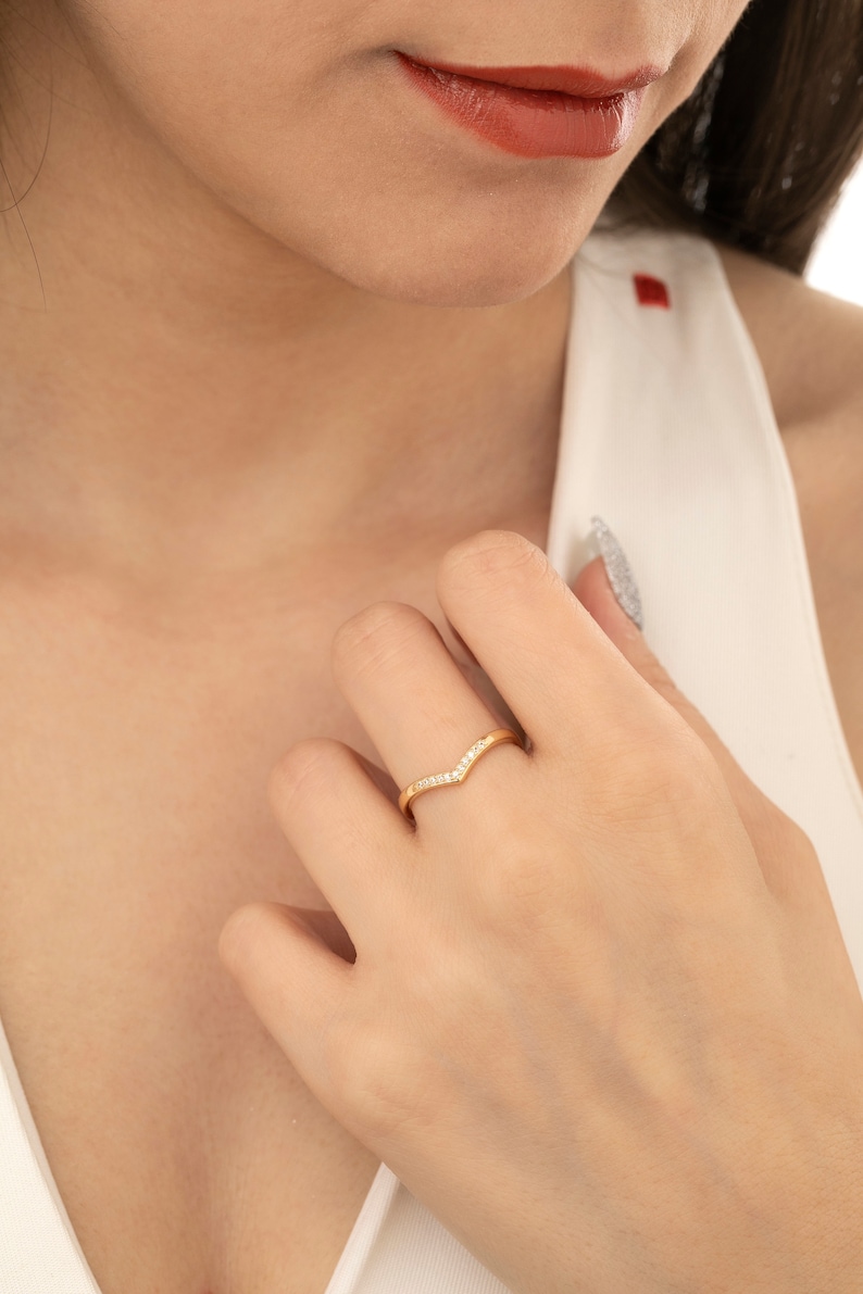May include: A gold ring with a V-shaped design and small clear stones.