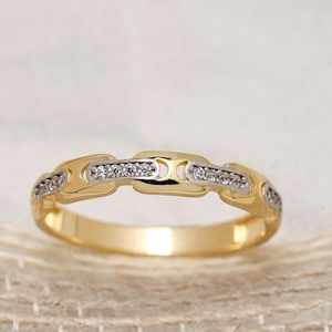 Puede incluir: Un anillo de banda de oro y plata con un diseño de cadena y pequeñas piedras transparentes engastadas en la banda.