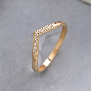 May include: A gold ring with a V-shaped band and small clear stones set along the top edge.