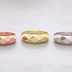 May include: Three geometric rings in different metal finishes: rose gold, yellow gold, and silver.