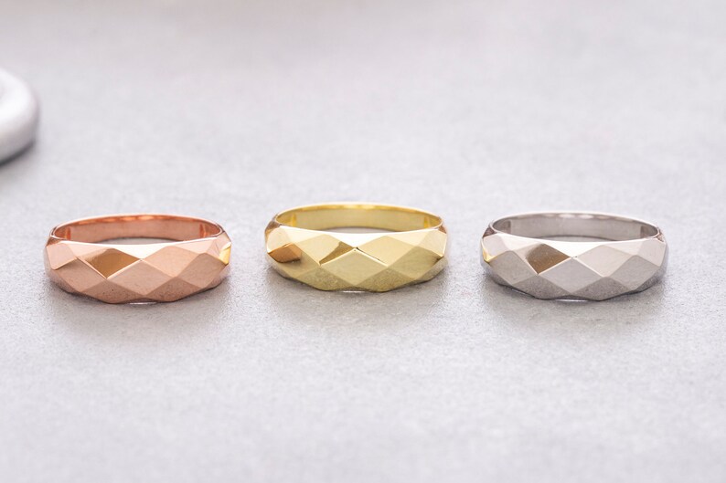 May include: Three geometric rings in different metal finishes: rose gold, yellow gold, and silver.