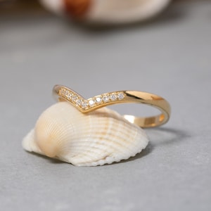 May include: A gold ring with a V-shaped band of small diamonds.