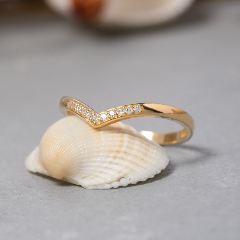 May include: A gold ring with a V-shaped band of small diamonds.