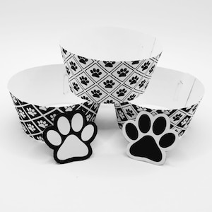 May include: Three black and white cupcake cases with a paw print pattern. Two black and white paw print cupcake toppers are also included.