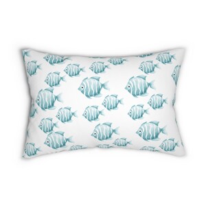 May include: A white pillow with a repeating pattern of teal blue fish. The fish have white stripes and are facing to the right.