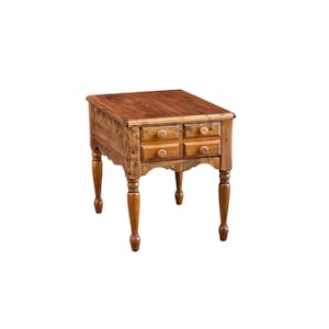 May include: A small, wooden side table with a warm, brown finish. It features four small drawers with round knobs and decorative, turned legs. The table has a scalloped apron and a rectangular top.