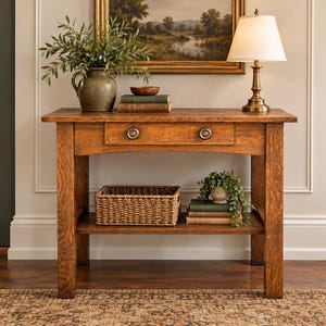 May include: A rectangular wooden console table with a natural grain finish, featuring a single drawer with two round metal knobs. The table has a lower shelf, four sturdy legs, and a flat top surface for displaying decorative items.