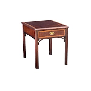 May include: A square wooden side table featuring a dark brown top surface with a lighter wood border. The table includes a single front-facing drawer with a brass-colored oval pull handle and four straight legs connected by decorative corner brackets.