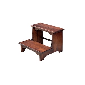 May include: A two-step wooden stool featuring a dark brown finish with a visible wood grain pattern. The stool has a rectangular top step and a lower step, supported by side panels with curved cutouts at the base and a horizontal support bar.