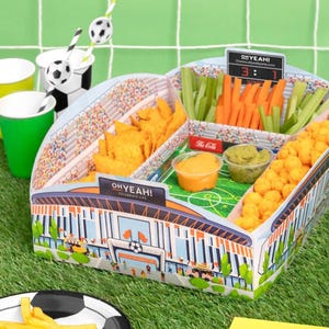 Op de afbeelding: Een voetbal-thema snackbak met compartimenten voor chips, kaassoufflés, wortel- en selderijstengels en dips. De bak is versierd met een stadionontwerp en de tekst "OH YEAH! CELEBRATE LIFE". Inclusief voetbal-thema bekers en rietjes.