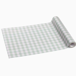 Puede incluir: Un rollo de papel a cuadros verde claro y blanco. El papel está desenrollado, revelando un patrón de cuadros. El rollo está sobre un fondo blanco.