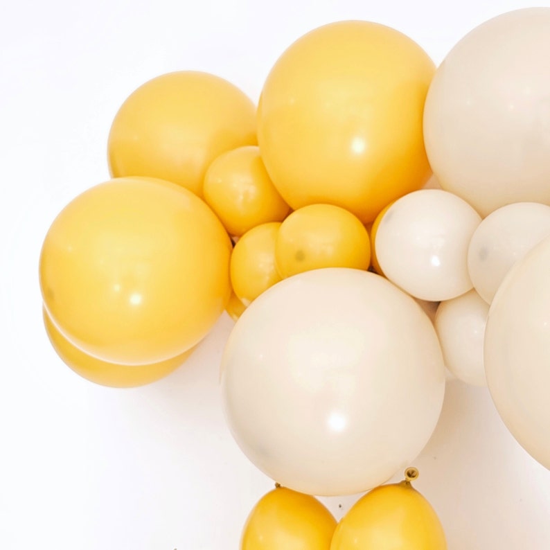 May include: A cluster of cream and yellow balloons, perfect for a party or special occasion.