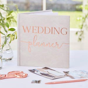 Puede incluir: Un planificador de bodas gris con las palabras "Wedding Planner" en letras doradas.