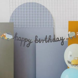 Puede incluir: Una guirnalda negra con la frase "happy birthday" y recortes decorativos de vehículos. El fondo presenta una rejilla azul claro, paneles grises y amarillos, y globos.