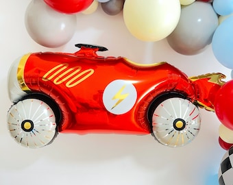 May include: Red race car balloon with a lightning bolt and the number 000 printed on it. The balloon is surrounded by colorful balloons.