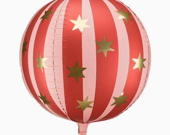 May include: A spherical foil balloon featuring alternating vertical stripes in red and light pink. The surface is decorated with multiple five-pointed gold stars scattered across the striped pattern. The balloon has a small inflation tab at the bottom.