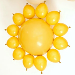 May include: A cluster of yellow balloons arranged in a circle, resembling a sun. The balloons are all the same size and shape, and they are all inflated to the same level.