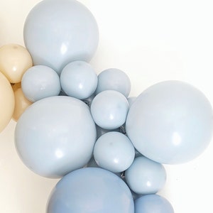 May include: A cluster of light blue and cream balloons, arranged in a garland or arch shape. The balloons are various sizes and are tied together.