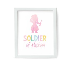 Può includere: Una stampa incorniciata bianca con una silhouette rosa ad acquerello di una persona che tiene una spada. Il testo "SOLDIER of Hashem" è scritto in colori arcobaleno sotto la silhouette.