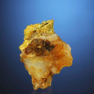 May include: A small piece of quartz with a cluster of gold nuggets on top. The quartz is a light brown colour and the gold is a bright yellow.