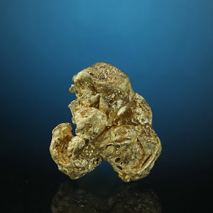 Puede incluir: Una pepita de oro grande e irregular. El oro tiene una superficie rugosa y texturizada y es de un color amarillo intenso y rico.