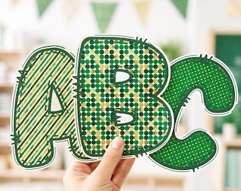 May include: Three large, die-cut letters A, B, and C featuring green and gold patterns. The letter A has diagonal stripes, the letter B has a dense polka dot pattern, and the letter C has a smaller dot pattern, all with dark green outlines.