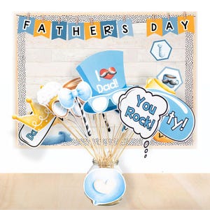 Pode incluir: Um conjunto de adereços para cabine de fotos do Dia dos Pais em azul, amarelo e branco. Os adereços incluem uma coroa, óculos, um bigode, um balão de fala que diz "You Rock!" e um chapéu que diz "I Love Dad!"