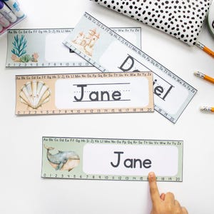 May include: Three printable name tags with a seashell, a whale, and a castle design. Each tag has a line for writing a name and a number line from 0 to 20. The name "Jane" is written on two of the tags.