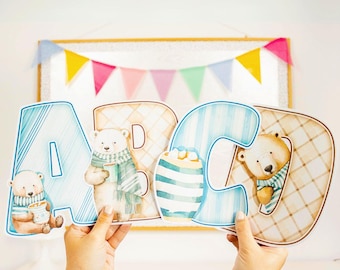 May include: A set of three blue and white alphabet letters, A, B, and C, with a brown and white plaid pattern. Each letter features a cartoon polar bear wearing a blue and white scarf and holding a cup of hot chocolate.