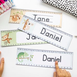May include: Three printable name tags with a jungle theme. Each tag features a different animal: a sloth, a koala, and a chameleon. The tags include a line for writing a name and a number line from 0 to 20.