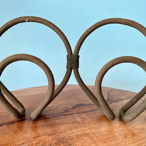 Puede incluir: Una diadema de tela marrón con un diseño único de doble bucle. La diadema está hecha de un material suave y flexible y está diseñada para ser cómoda de llevar.