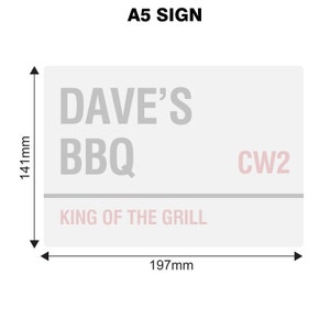 May include: A white A5 sign with gray text that reads "Dave's BBQ King of the Grill" and a pink postcode "CW2". The sign measures 197 mm by 141 mm.