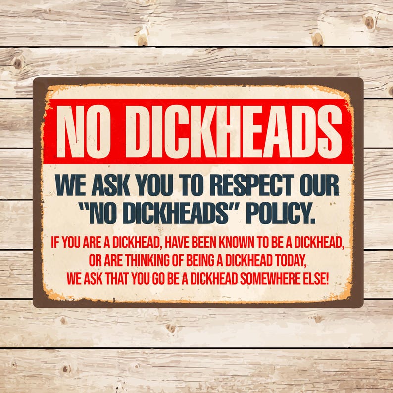 Op de afbeelding: Een rechthoekig metalen bord met een bruine rand en een houten achtergrond. Het bord heeft de woorden "NO DICKHEADS" in grote rode letters bovenaan. Daaronder staat "WE ASK YOU TO RESPECT OUR 'NO DICKHEADS' POLICY."