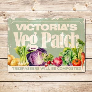 May include: A rectangular sign with the text "Victoria's Veg Patch" and "Trespassers Will Be Composted" in a vintage style. The sign features illustrations of various vegetables, including potatoes, cabbage, onions, radishes, and a tomato.
