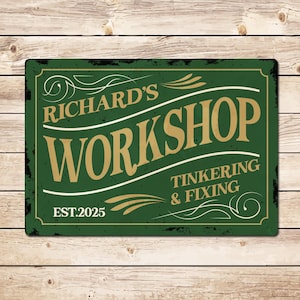 May include: A rectangular green metal sign with the text "RICHARD'S WORKSHOP" in gold lettering. The sign also includes the words "TINKERING & FIXING" and "EST.2025". The sign has a distressed look with black edges and white decorative flourishes.