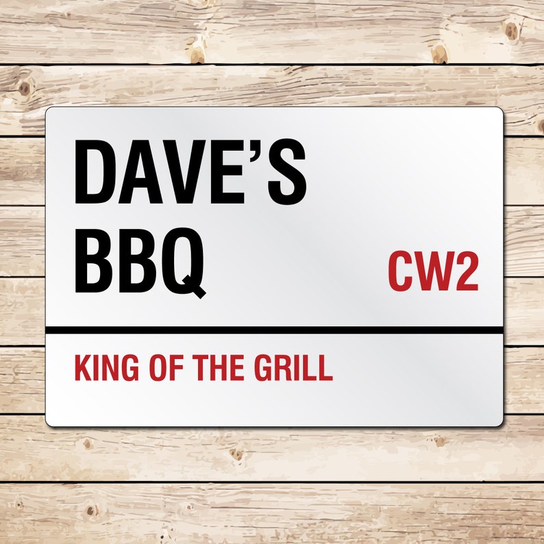 May include: White metal sign with black text that reads "Dave's BBQ" and "King of the Grill". The sign also has red text that reads "CW2".