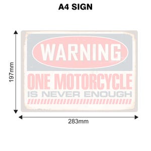 May include: A white sign with a pink warning sign that says "WARNING" in white text. The sign also says "ONE MOTORCYCLE IS NEVER ENOUGH" in black text. The sign is 11.7 inches by 8.4 inches.