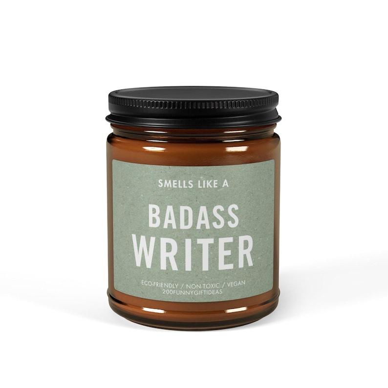 May include: A brown glass candle jar with a black lid. The label reads "Smells Like A Badass Writer" with the text "Ecofriendly / Non-Toxic / Vegan 200funnygiftideas" below.
