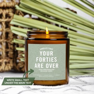 May include: A brown glass candle jar with a green label that reads "Smells like your forties are over. Your personalized message here! Eco-friendly/Non-toxic/Vegan 200funnygiftideas".