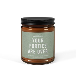 May include: A brown glass candle jar with a black lid. The label reads "Smells Like Your Forties Are Over" with the text "ECO-FRIENDLY / NON-TOXIC / VEGAN 200FUNNYGIFTIDEAS" below.