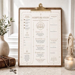 May include: A wooden clipboard holding a white Scripture Study worksheet with gold-toned text and borders. The page includes sections for prayer, reading, understanding, reflection, and application, featuring a central open book icon.