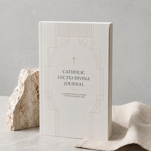 Puede incluir: Un diario blanco titulado Catholic Lectio Divina Journal, A Guided Scripture Journal for the Liturgical Year. La portada presenta un dibujo de líneas grises finas de un arco arquitectónico con un pequeño símbolo de cruz sobre el texto.