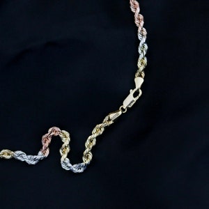 May include: A gold, silver, and rose gold rope chain necklace with a lobster clasp closure.