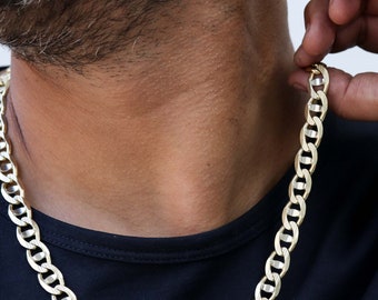 May include: A gold chain necklace with a curb link design. The chain is thick and has a shiny finish.